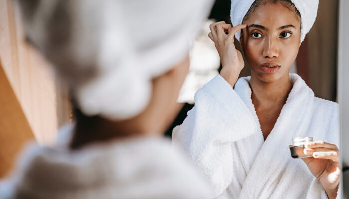 Woman rubbing cream on face after bath